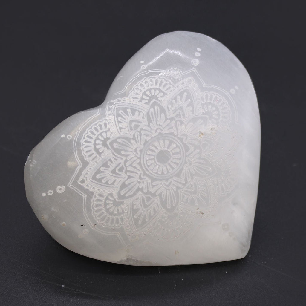 Heart-shaped stone with mandala design on a black background