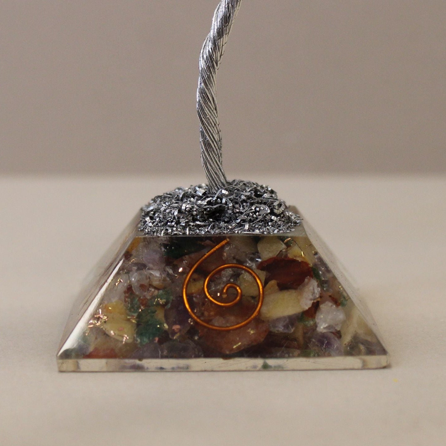 Pyramid-shaped crystal with a spiral design on a neutral background