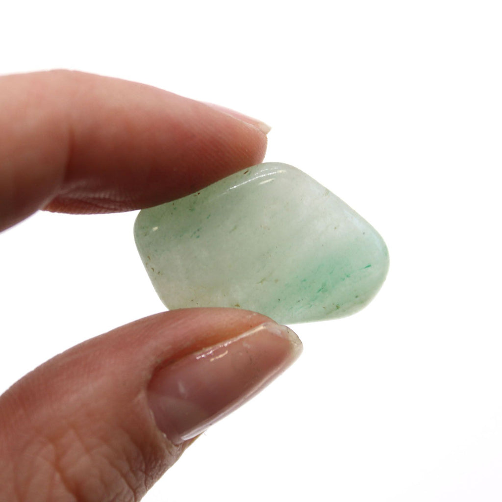 Hand holding a greenish stone against a white background