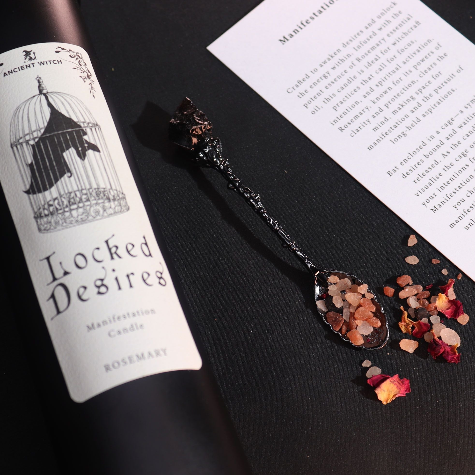 Spoon with dried flowers and a label for 'Locked Desires' candle on a black surface.