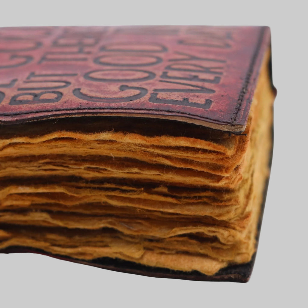 Close-up of a vintage book with worn leather cover and text.