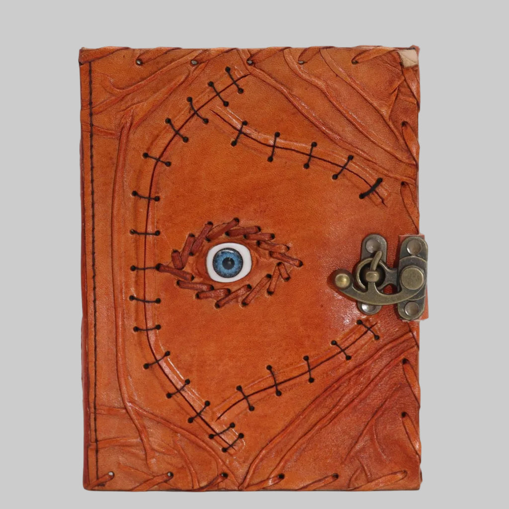 Brown leather journal with eye design and metal clasp on a white background