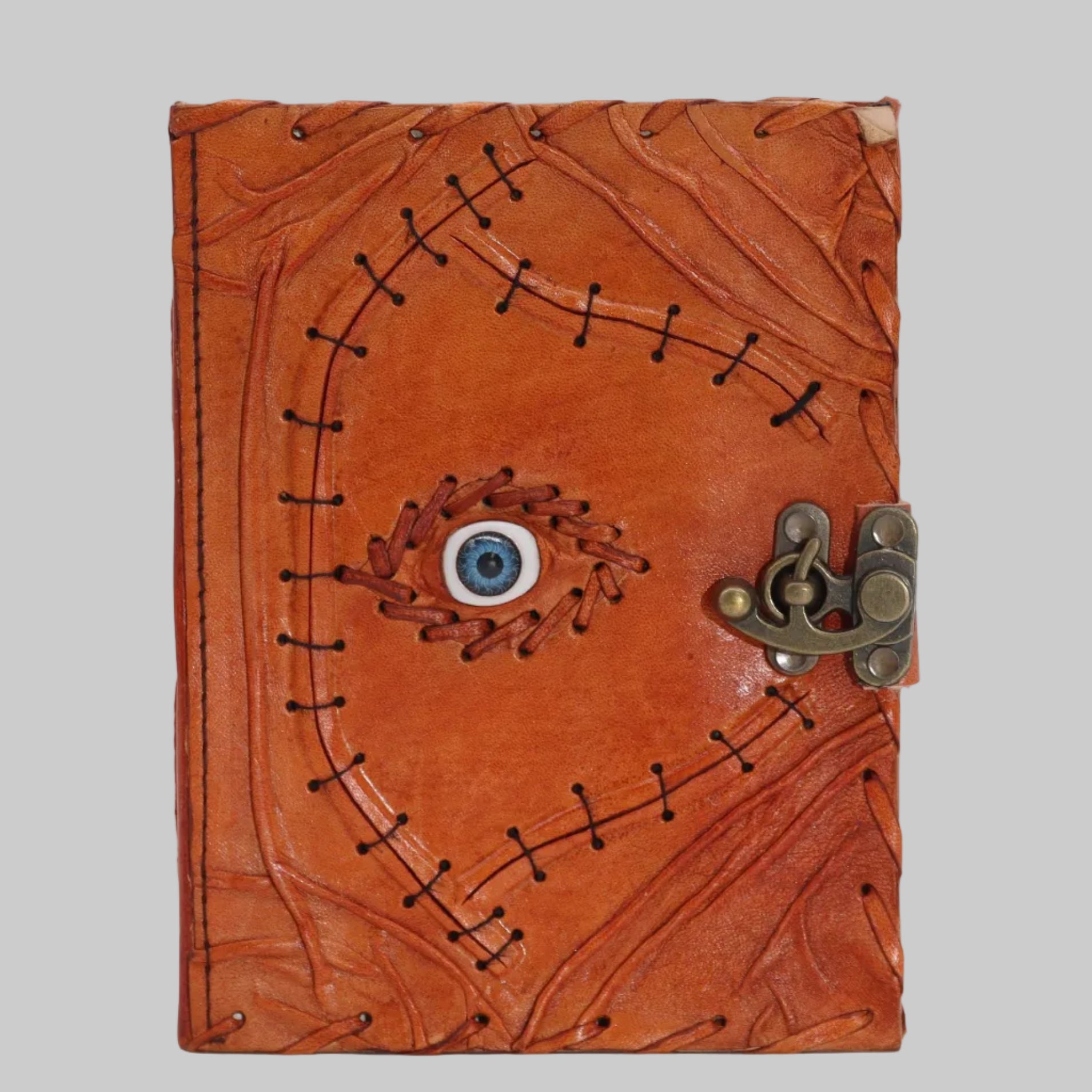 Brown leather journal with eye design and metal clasp on a white background