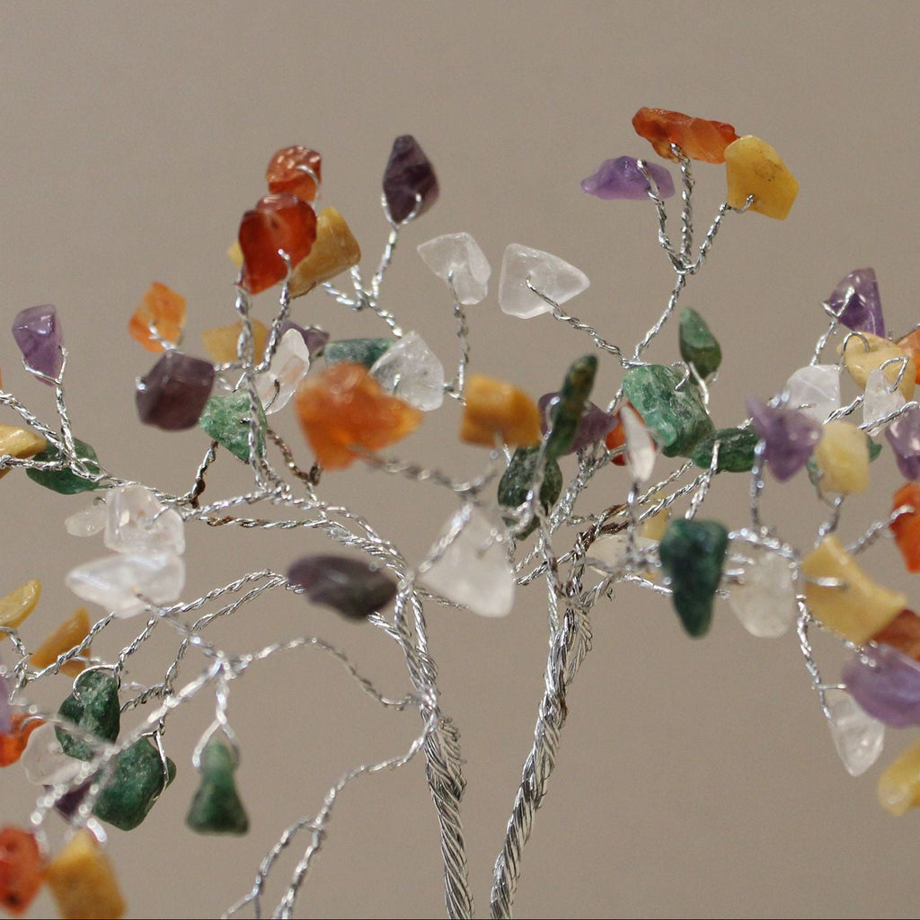 Decorative branch with multicolored stones on a plain background