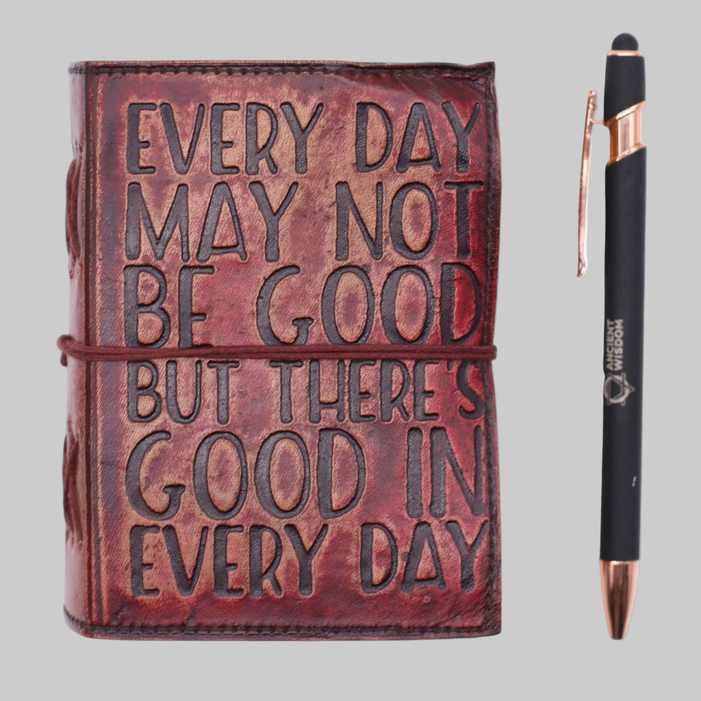 Brown leather journal with embossed text and a pen on a white background