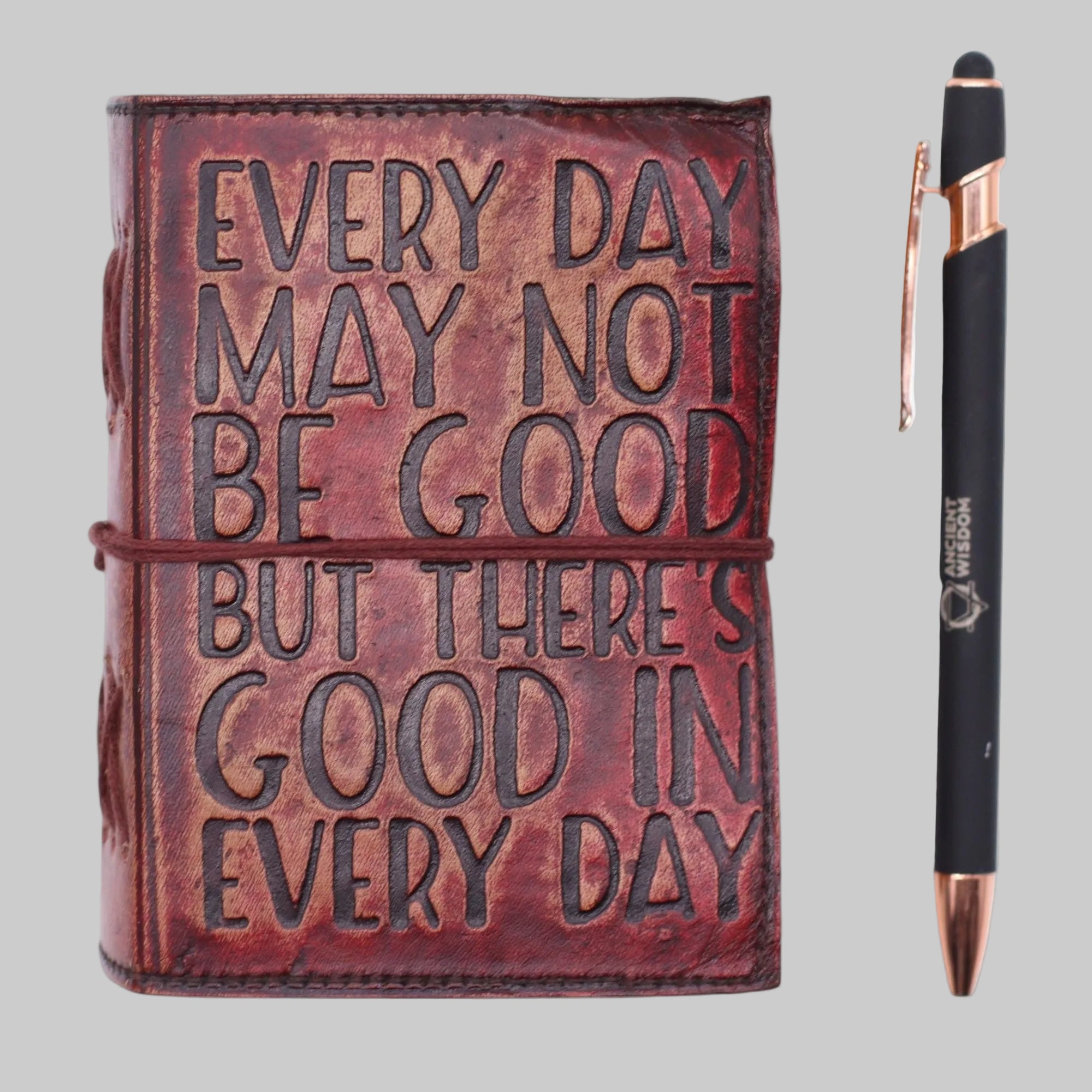Brown leather journal with embossed text and a pen on a white background