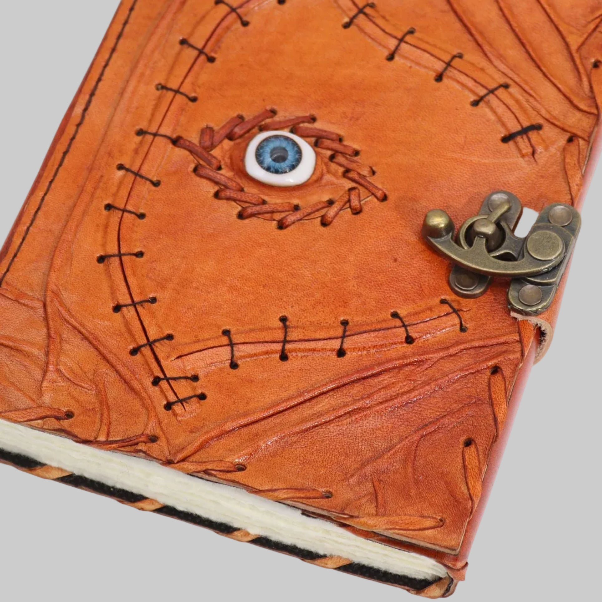 Brown leather notebook with eye design and metal clasp on a white background