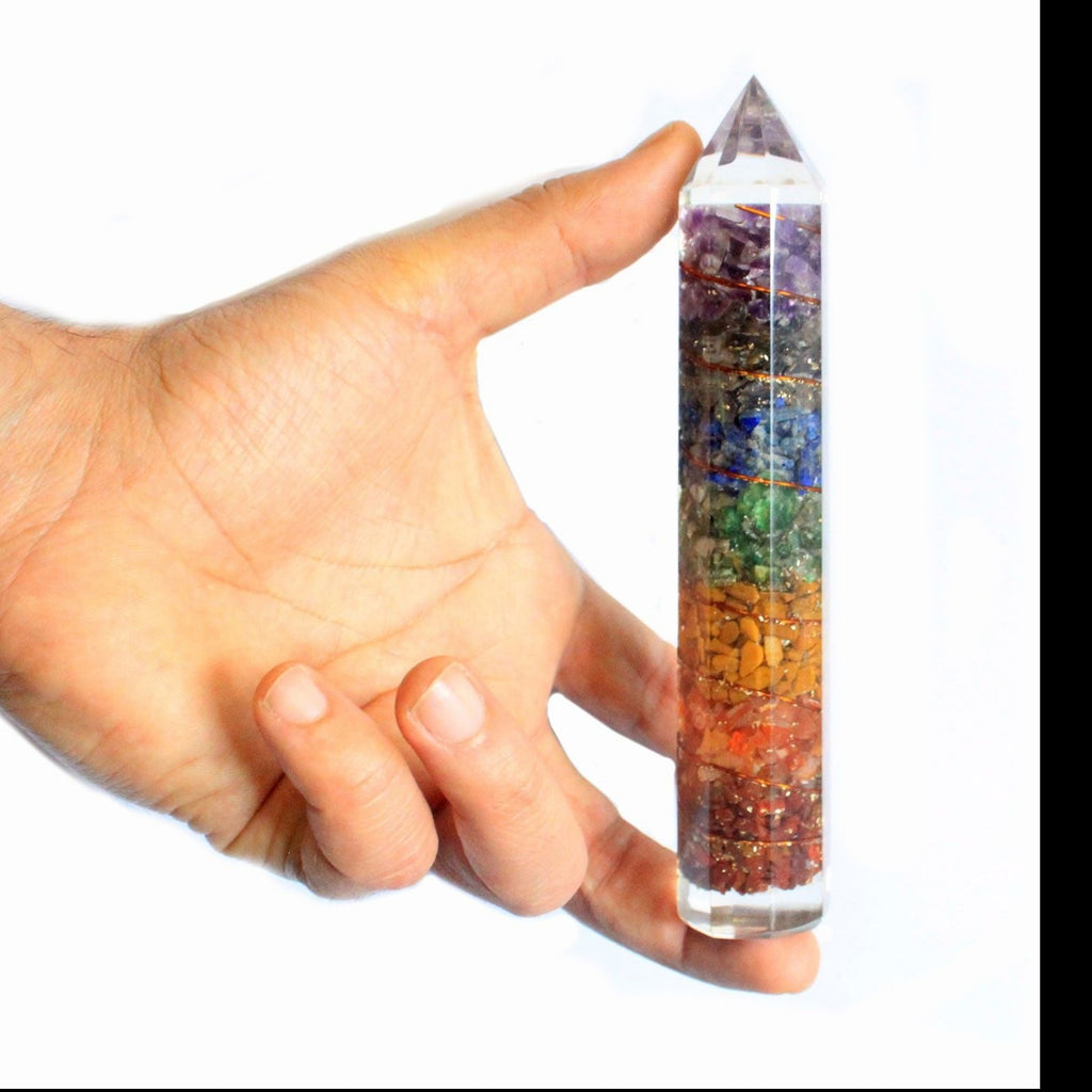 Hand holding a crystal with color layers against a white background