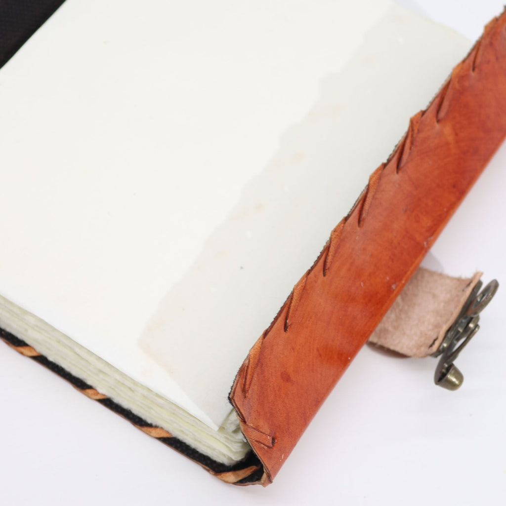 Close-up of a leather-bound notebook with a metal clasp on a white background