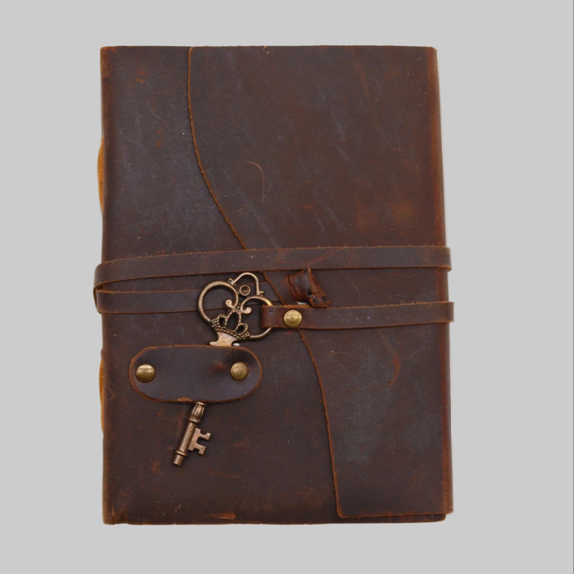 Brown leather journal with key charm on a white background