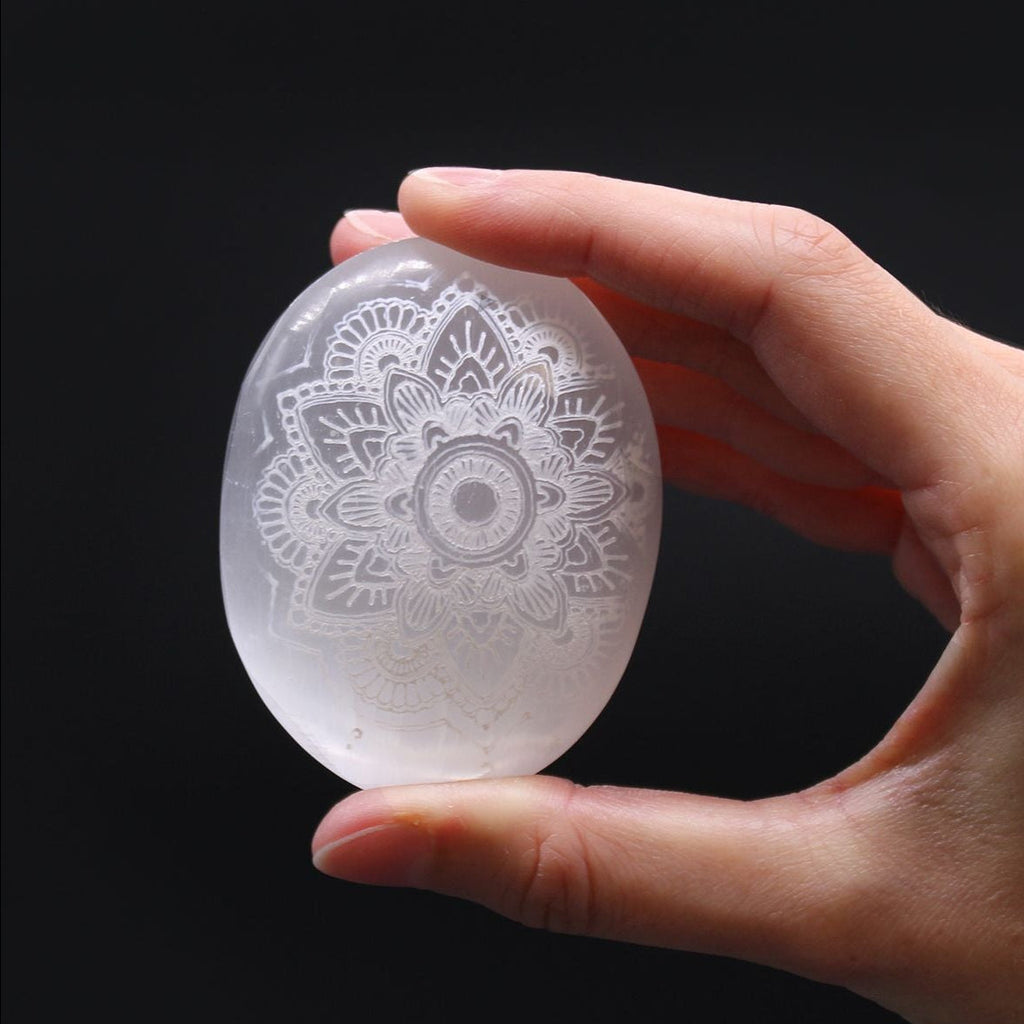 Hand holding a crystal egg with intricate patterns against a black background
