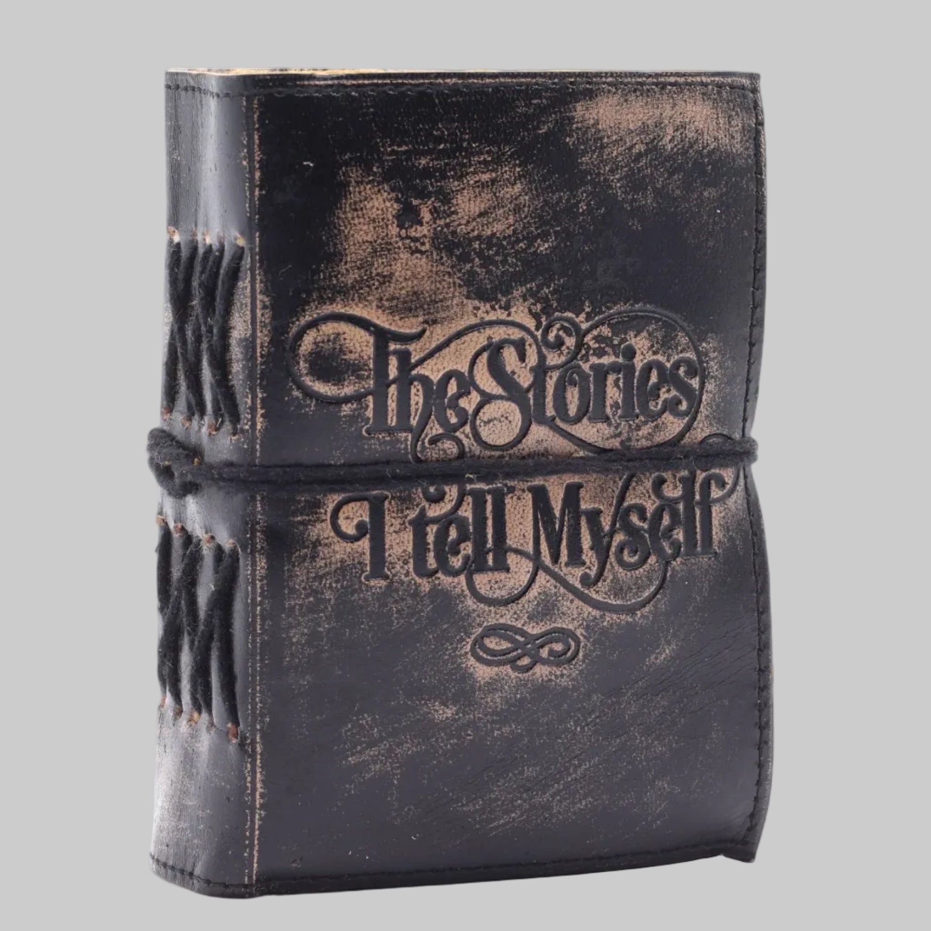 Vintage-style leather-bound book with 'The Stories I Tell Myself' text on a white background