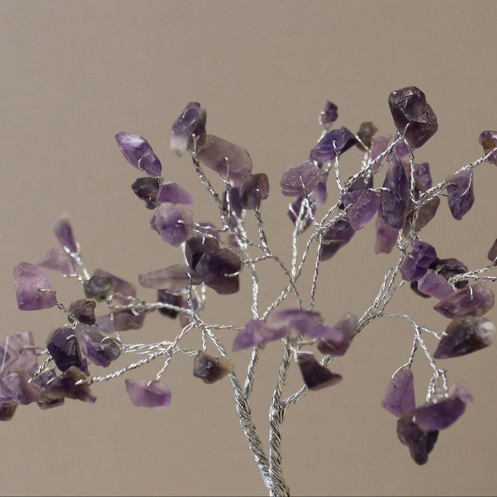 Decorative branch with purple crystal-like stones on a beige background
