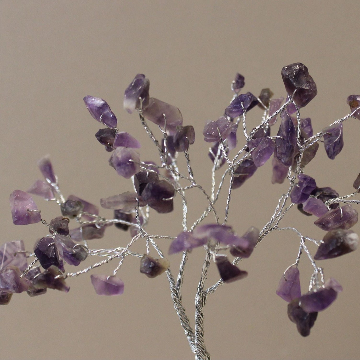 Decorative branch with purple crystal-like stones on a beige background