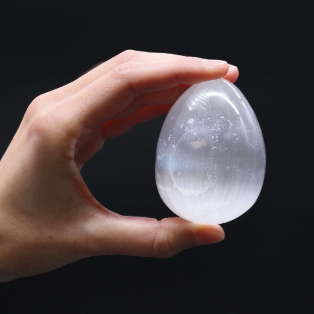 Hand holding a clear crystal ball against a black background
