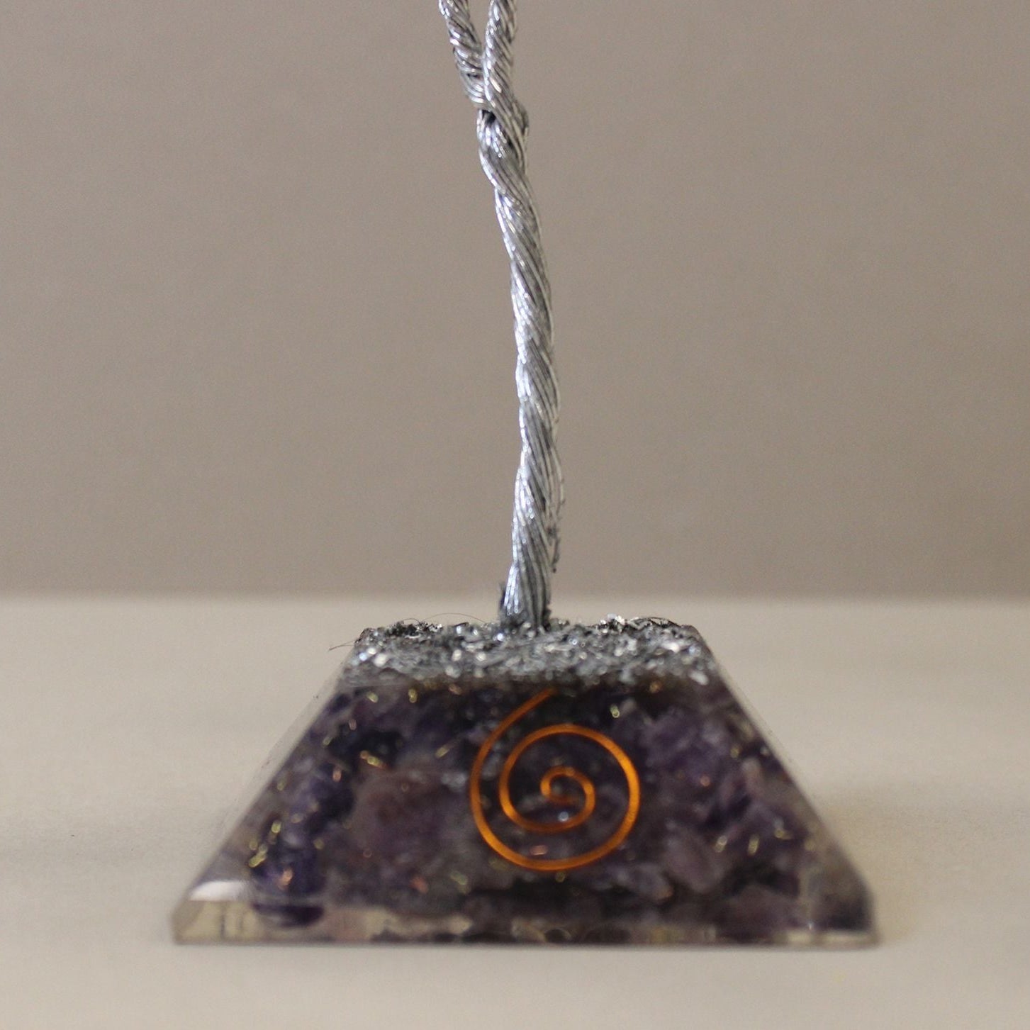 Pyramid-shaped crystal with spiral design on a beige background