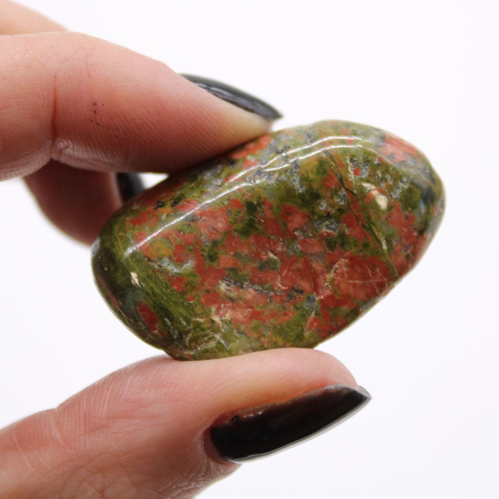 Hand holding a polished red and green stone against a white background
