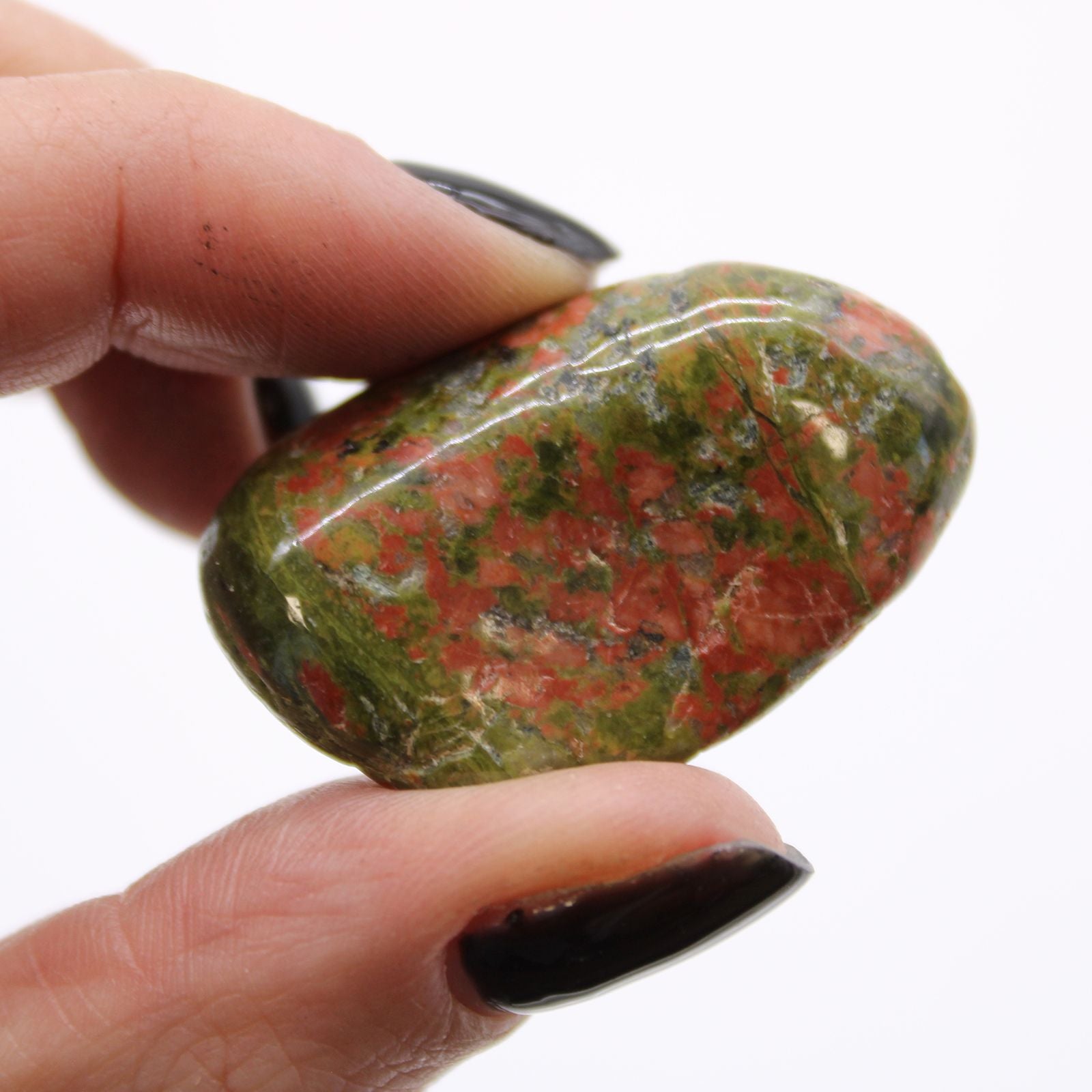 Hand holding a polished red and green stone against a white background