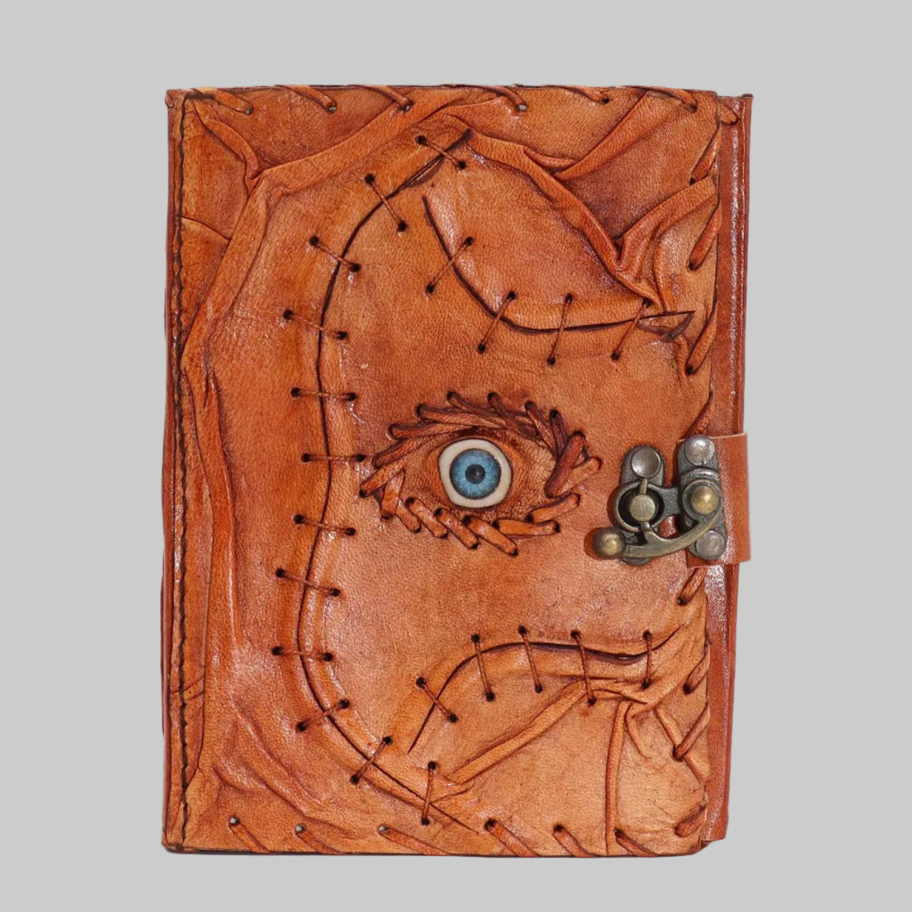 Brown leather journal with eye design and metal clasp on a white background