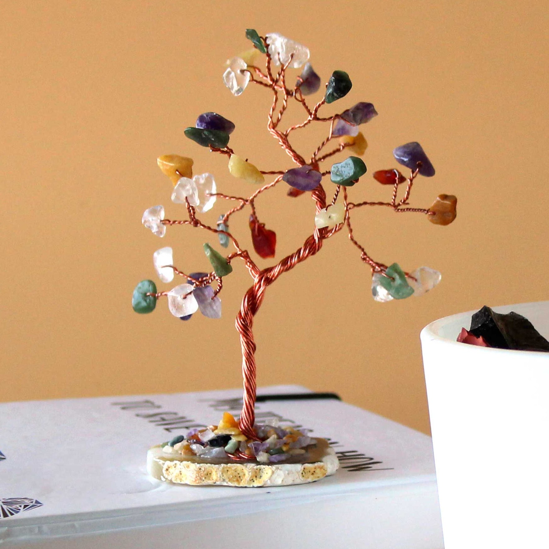 Decorative crystal tree on a book with a plain background