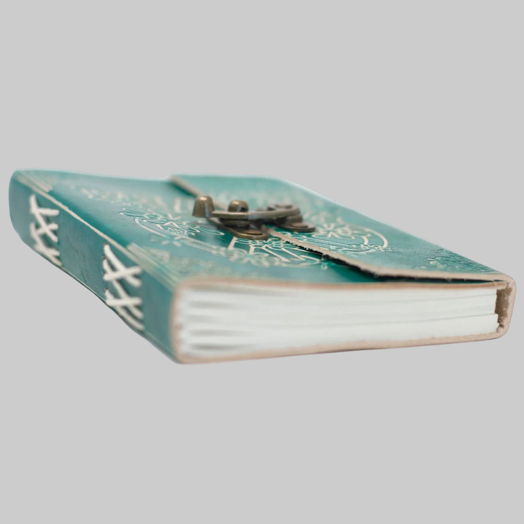 Green notebook with decorative cover and key on a white background