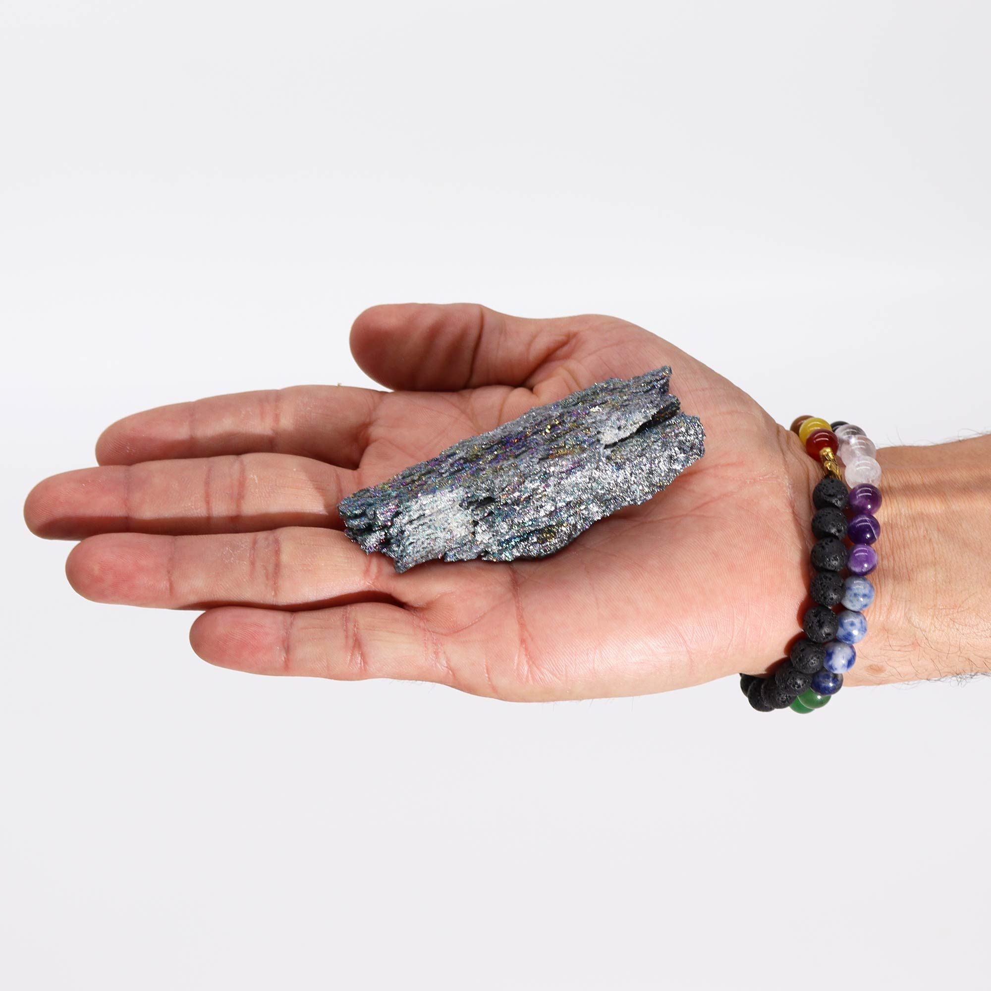 Hand holding a crystal rock with a colorful bracelet on a white background