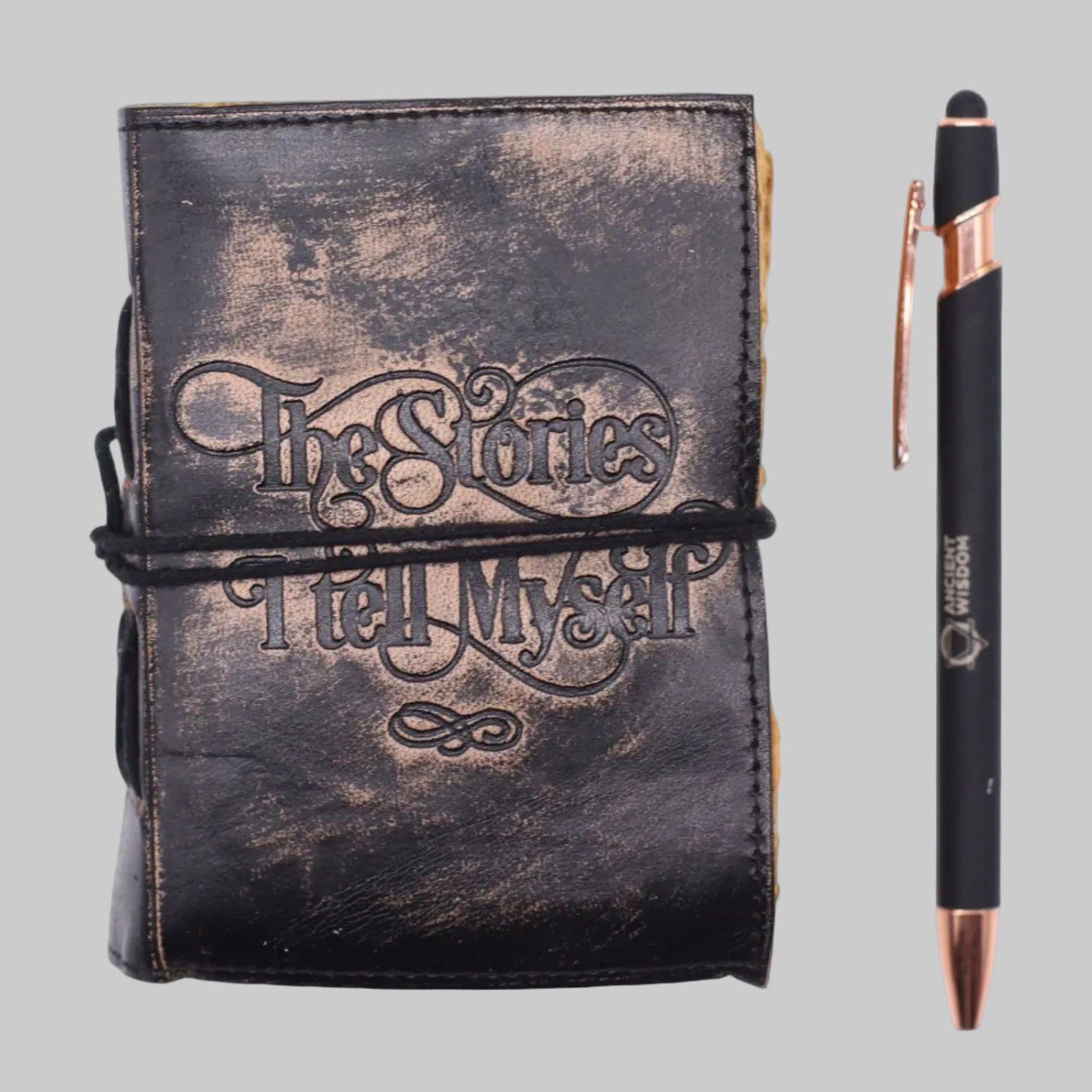 Black leather notebook with 'The Stories I Tell Myself' embossed text and a pen on a white background