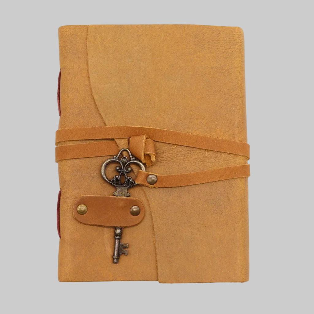 Brown leather journal with key charm on a white background