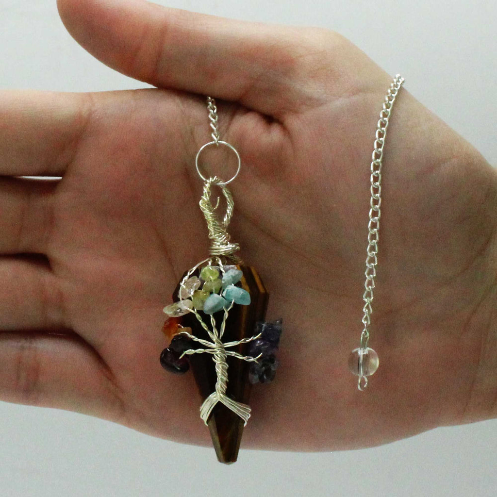 Hand holding a unique pendant with a chain against a plain background