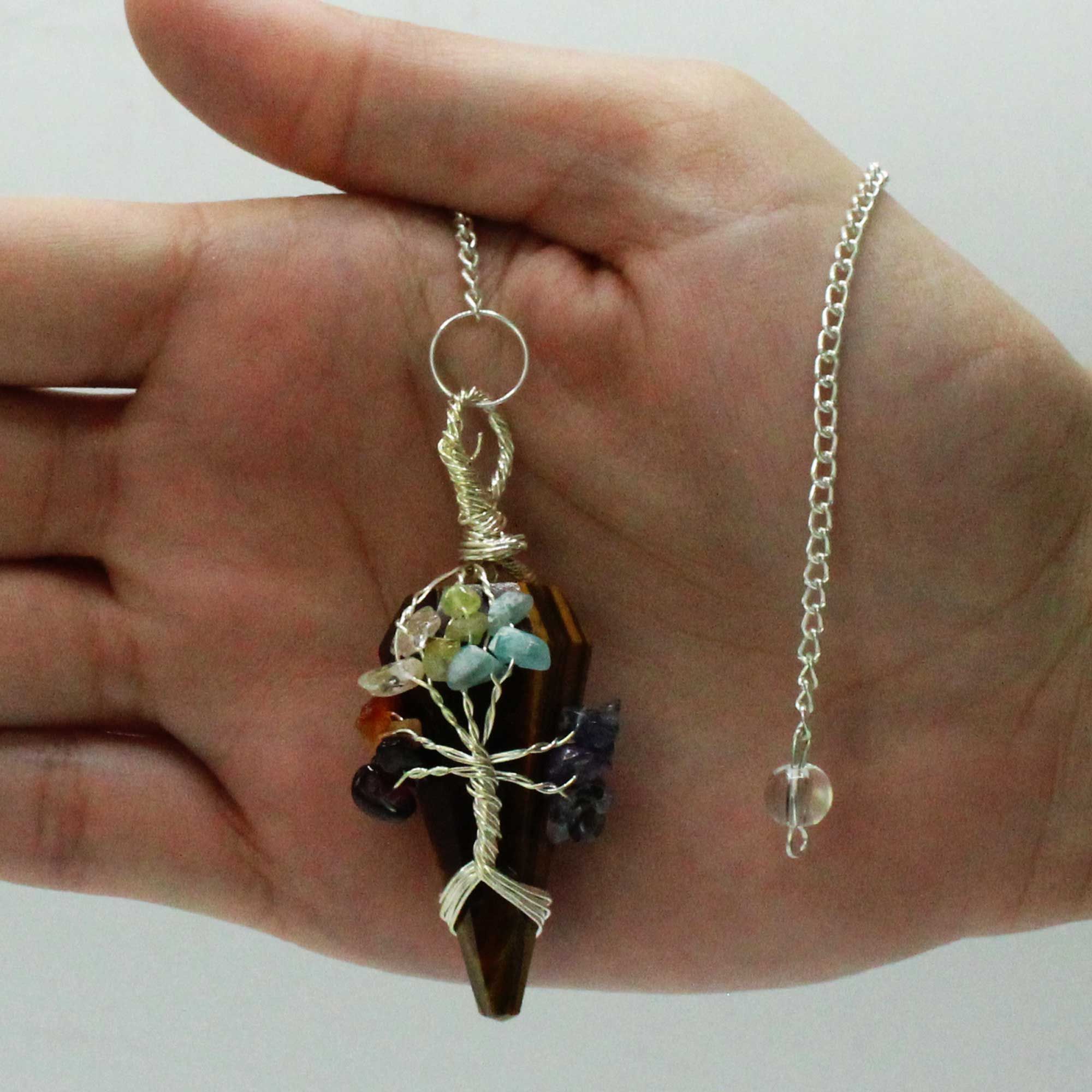 Hand holding a unique pendant with a chain against a plain background