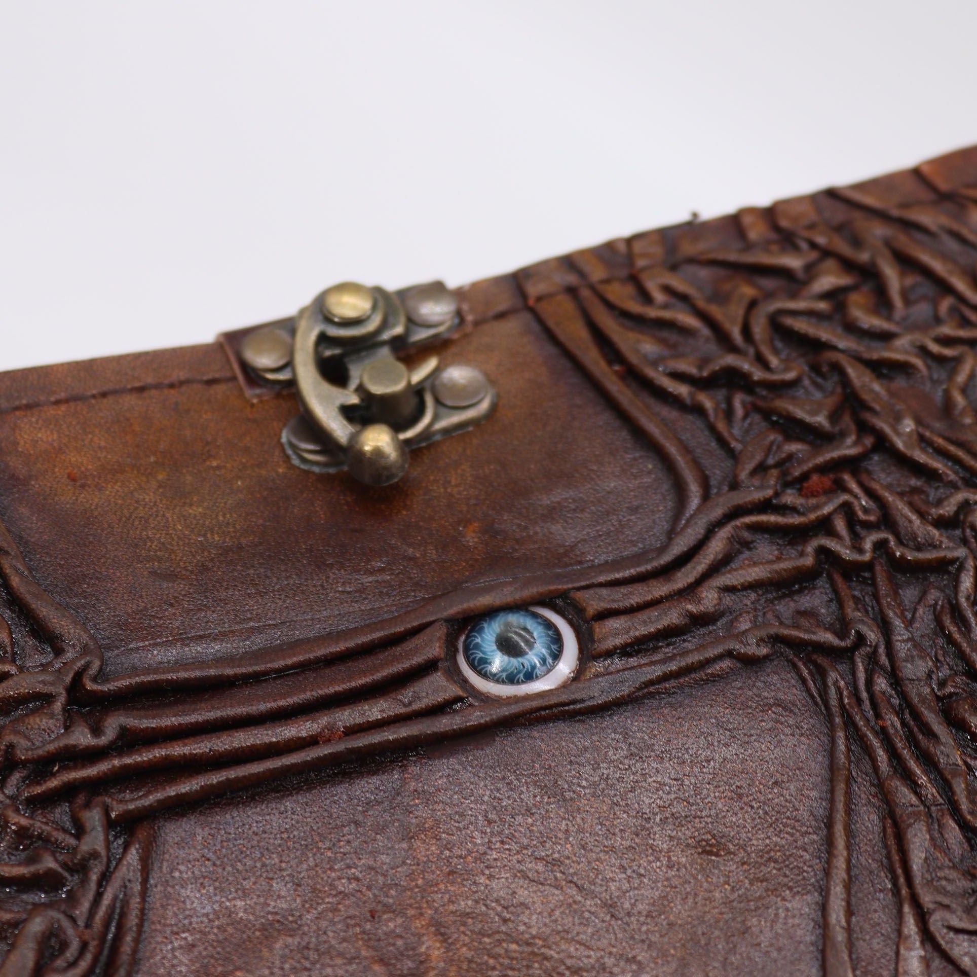 Close-up of a brown leather clutch with intricate designs and decorative elements.