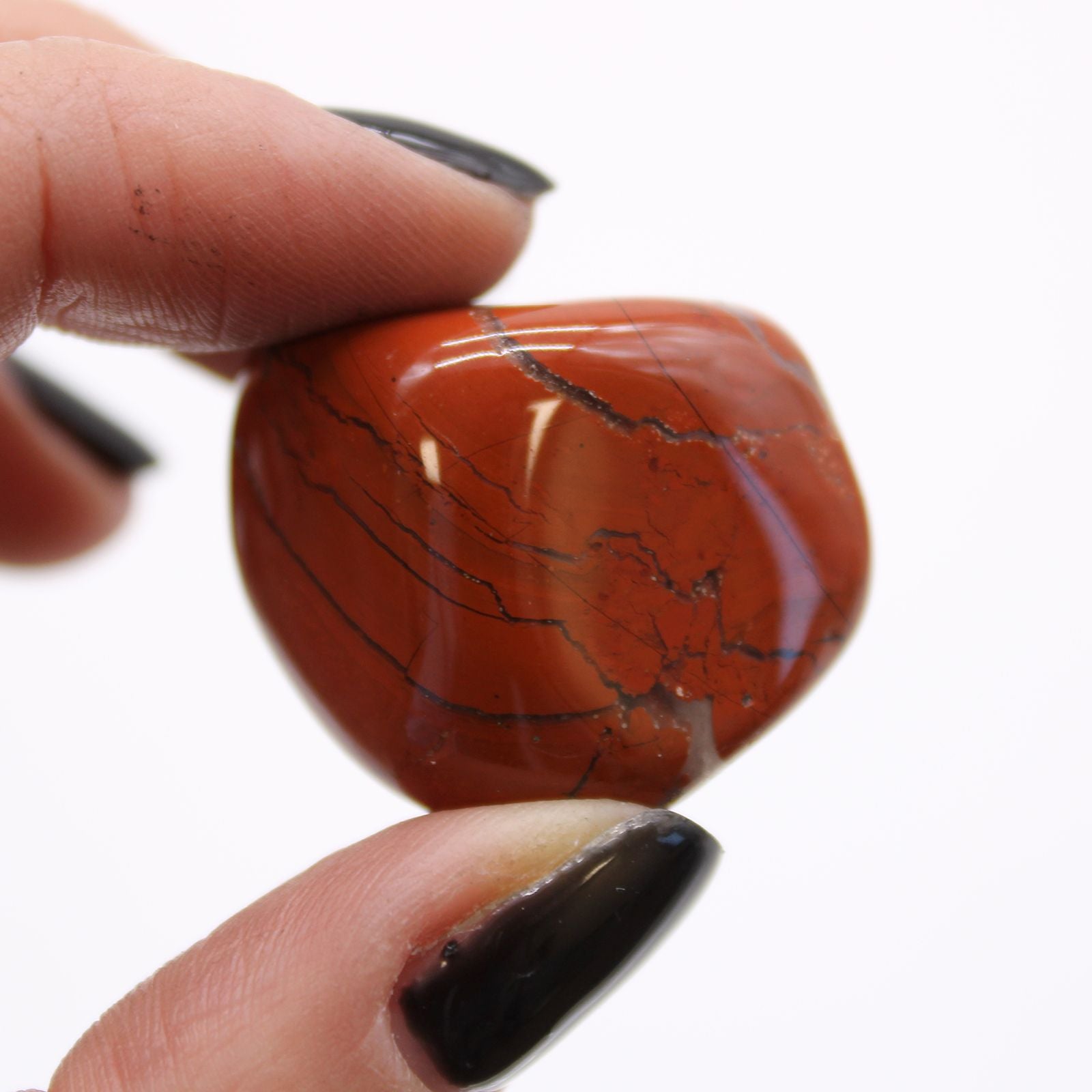 Hand holding a red marbled stone against a white background