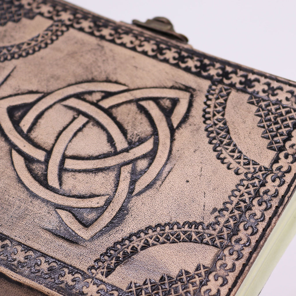 Close-up of a leather-bound book with Celtic knot design on a white background
