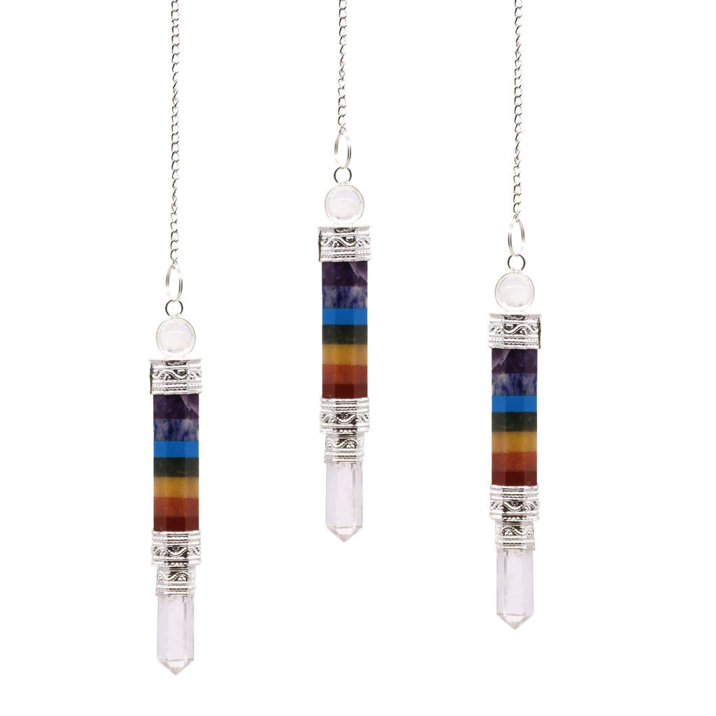 Three chakra crystal pendants on silver chains against a white background
