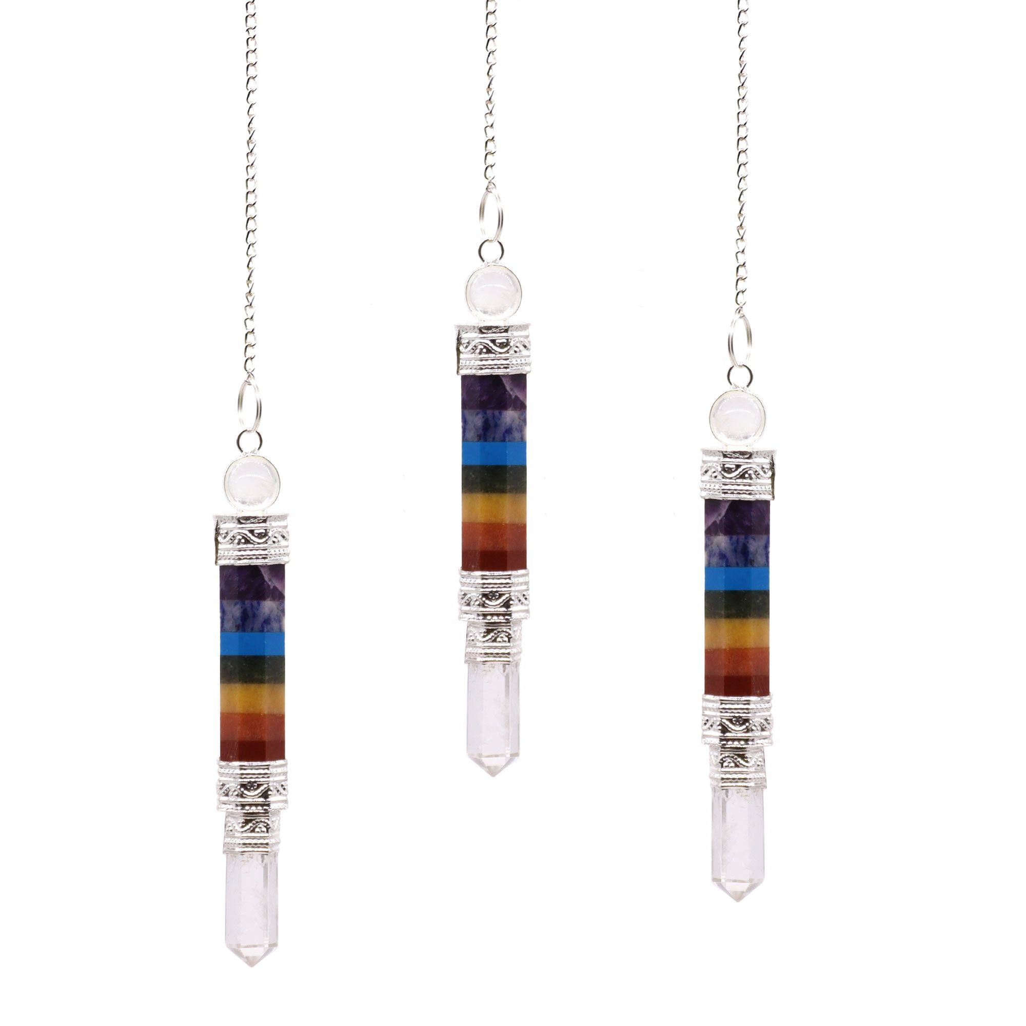 Three chakra crystal pendants on silver chains against a white background