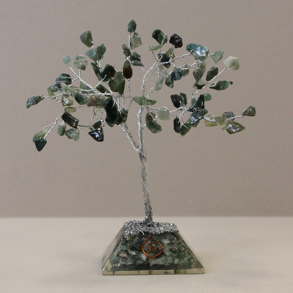 Decorative tree made of green stones on a beige base against a plain background