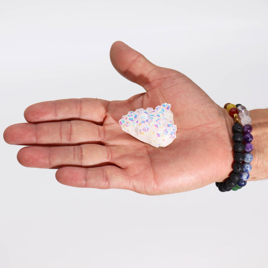 Hand holding a small crystal on a plain background