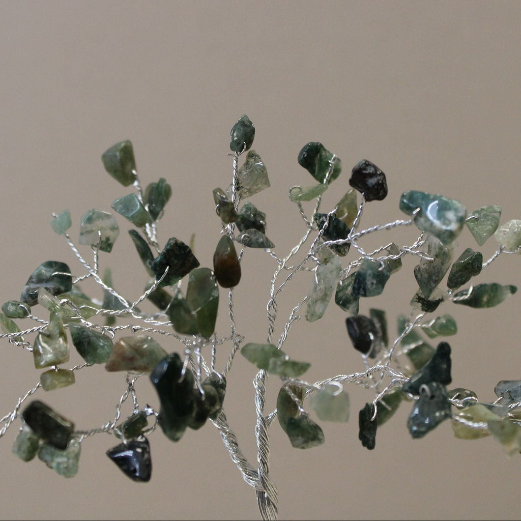 Decorative branch with green and black stones on a beige background