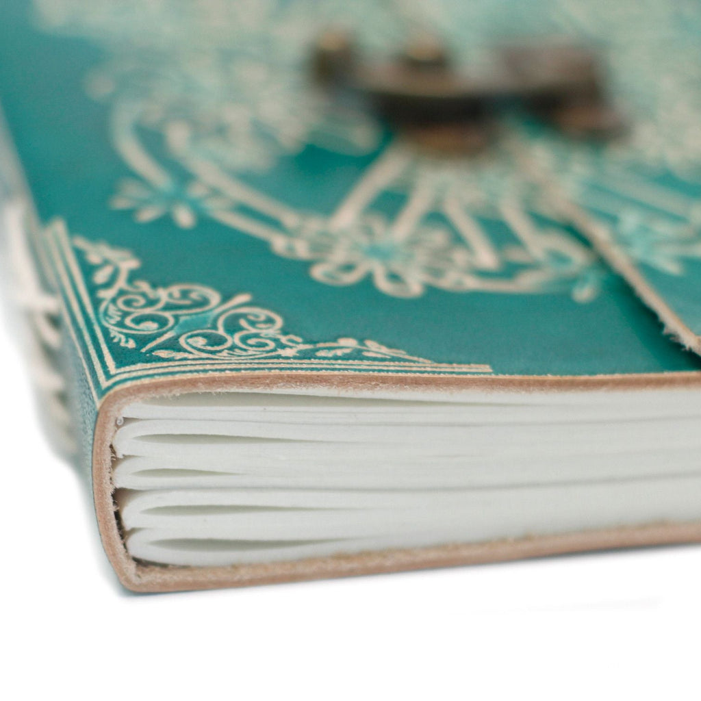 Close-up of a green notebook with decorative cover and white pages.