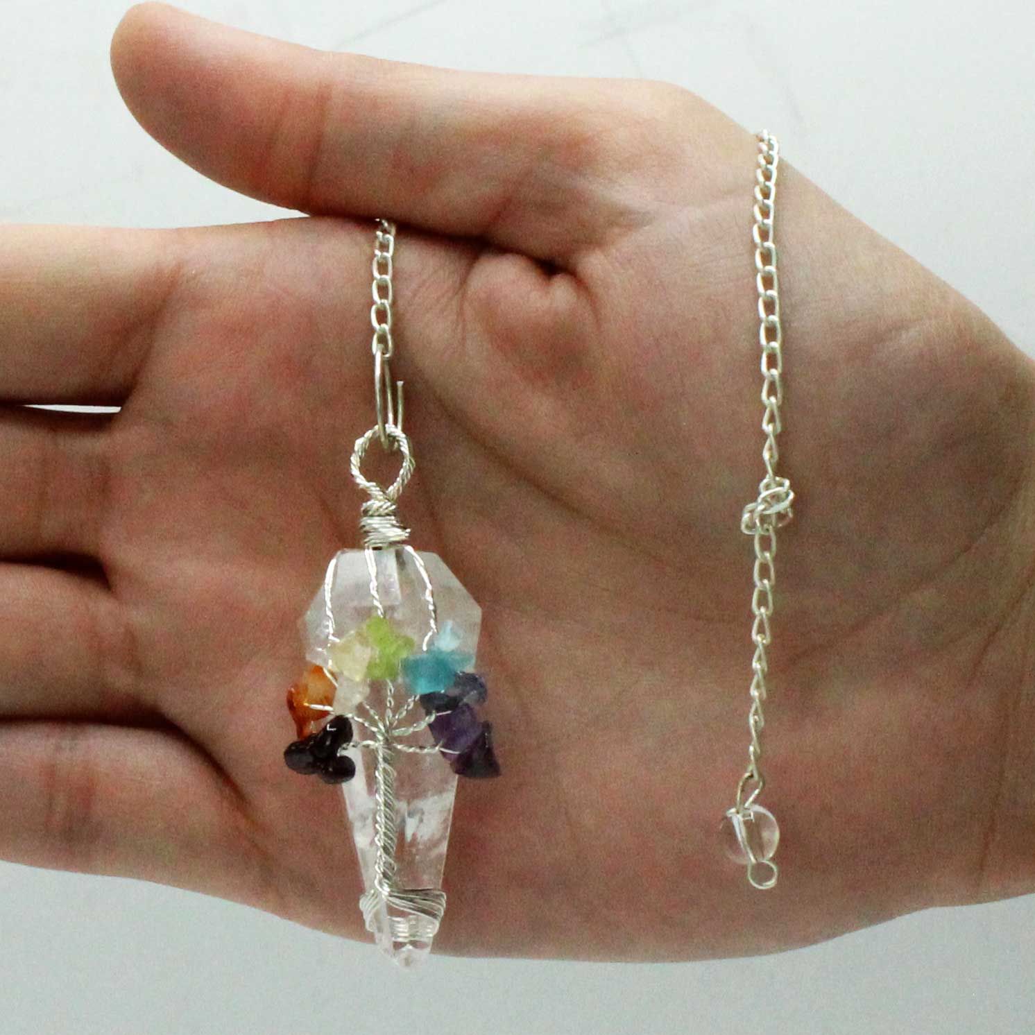 Crystal pendant necklace held in a hand against a white background