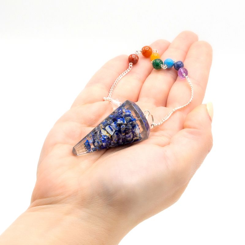 Hand holding a crystal pendulum with a colorful bead chain on a white background