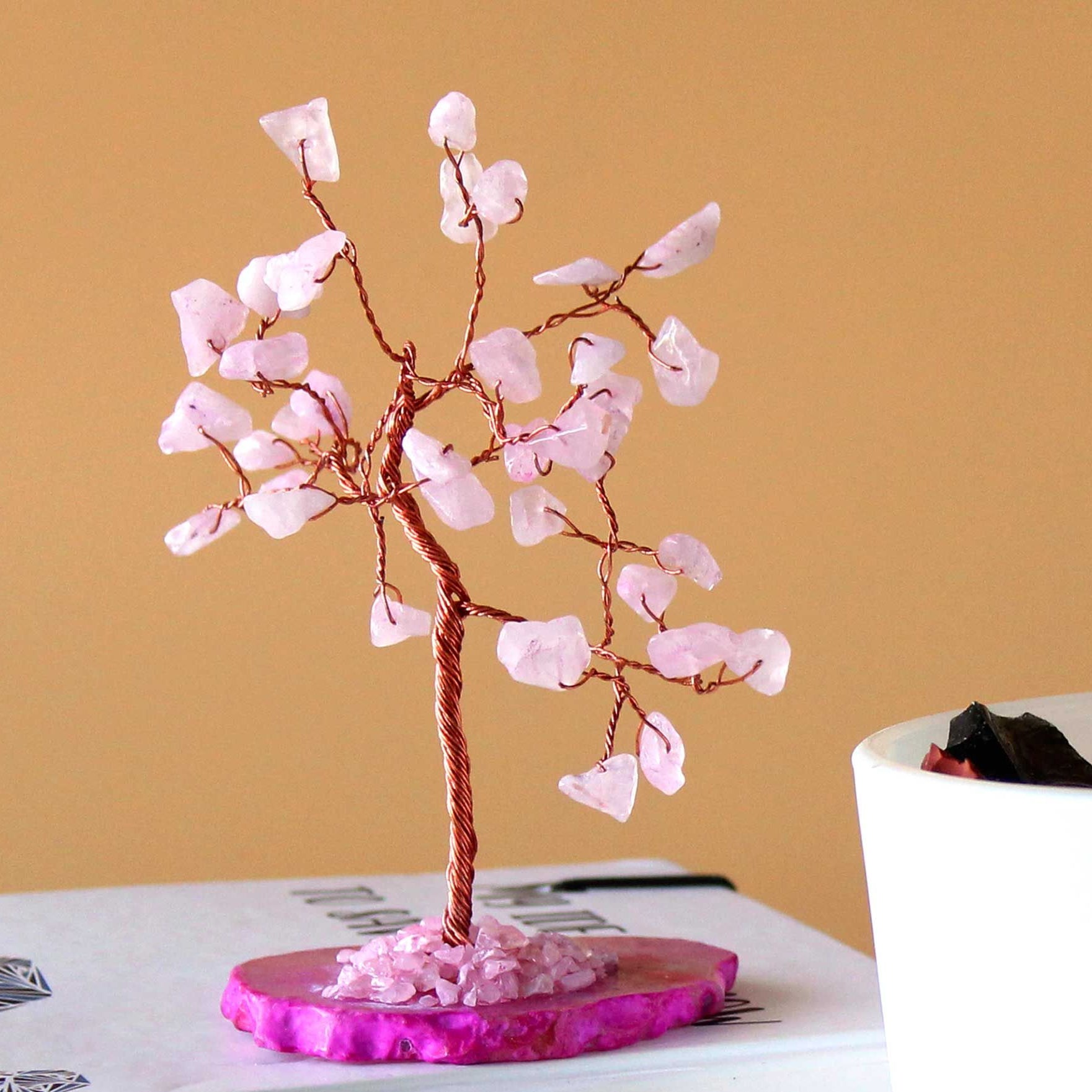 Decorative pink crystal tree on a book with a beige background