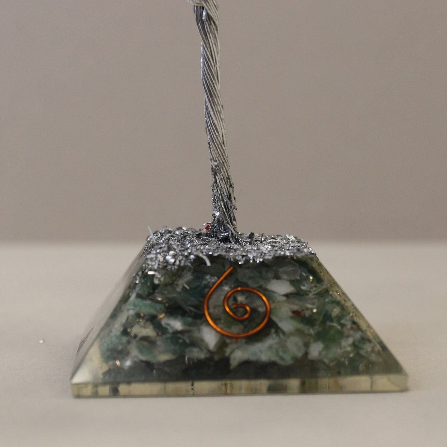 Pyramid-shaped object with a spiral design on a neutral background