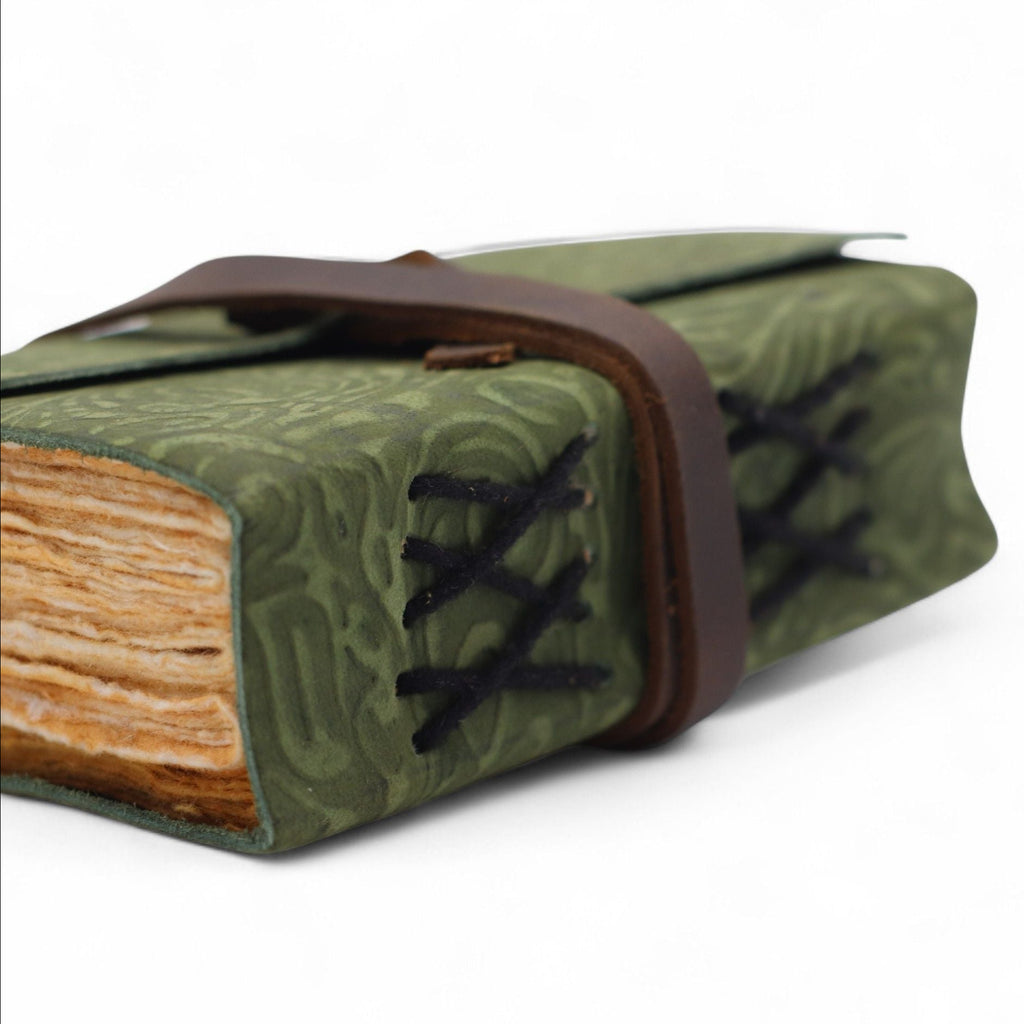 Green leather-bound book with a brown strap on a white background
