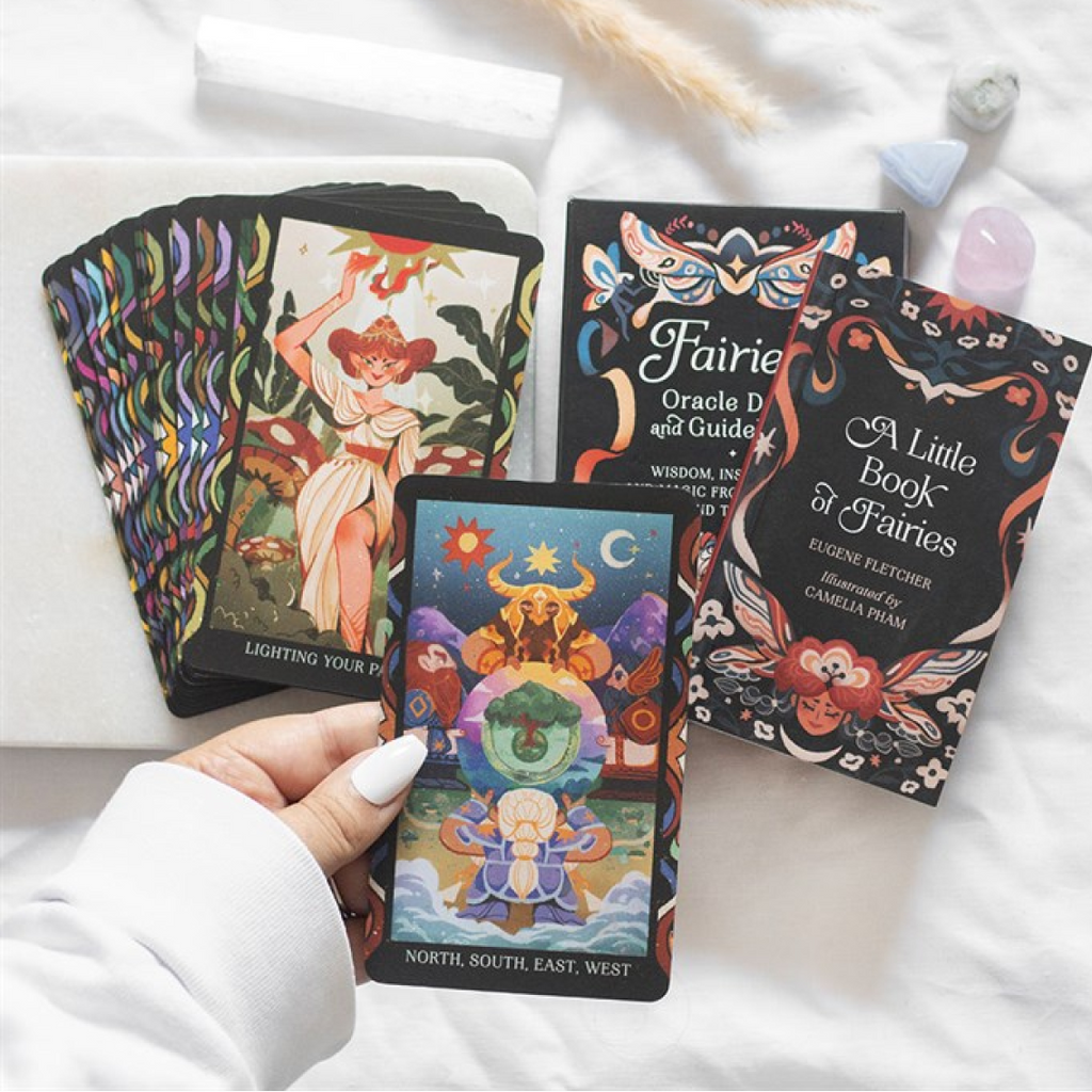 Colorful tarot cards and books on a white surface